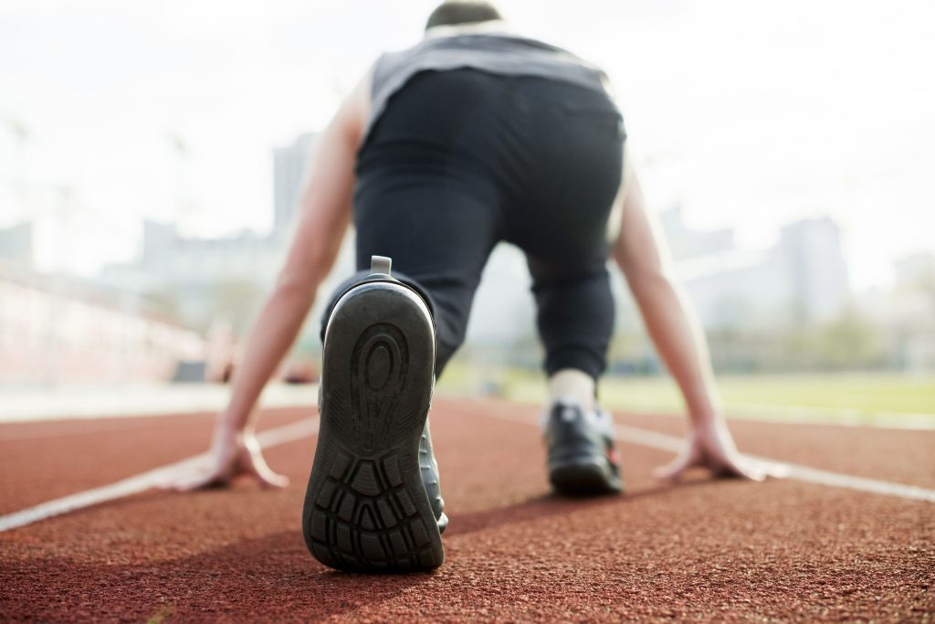 rear-view-male-athlete-taking-position-red-race-track